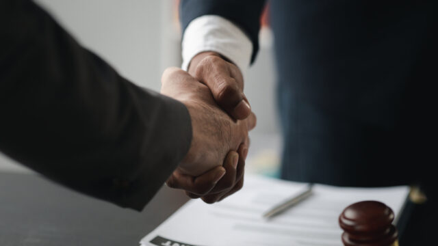 Lawyers shake hands with clients who come to testify in the case