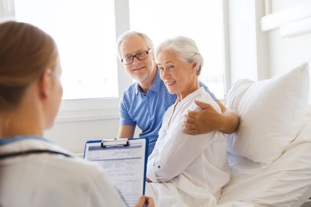 senior woman and doctor with clipboard at hospital