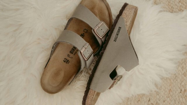 beige-Birkenstock-Schuhe_Sandalen-auf-weissem-Kunstfell-auf-cremefarbenen-Wollteppich-scaled-1.jpg