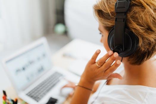 Woman at home using headphones and laptop for online work or video call.